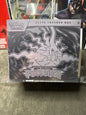 A sealed Pokémon Elite Trainer Box for Pitch Black from the 2024 TCG season, featuring a black and white graphic of Pitch Black on the front, photographed on a gray fabric surface.